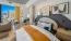a bedroom with a large bed a side table with a lamp and frames on the wall