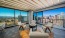 a room with a balcony and chairs and large windows