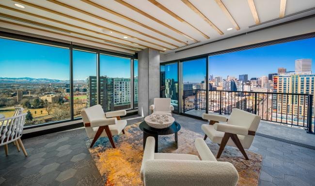 a room with a balcony and chairs and large windows